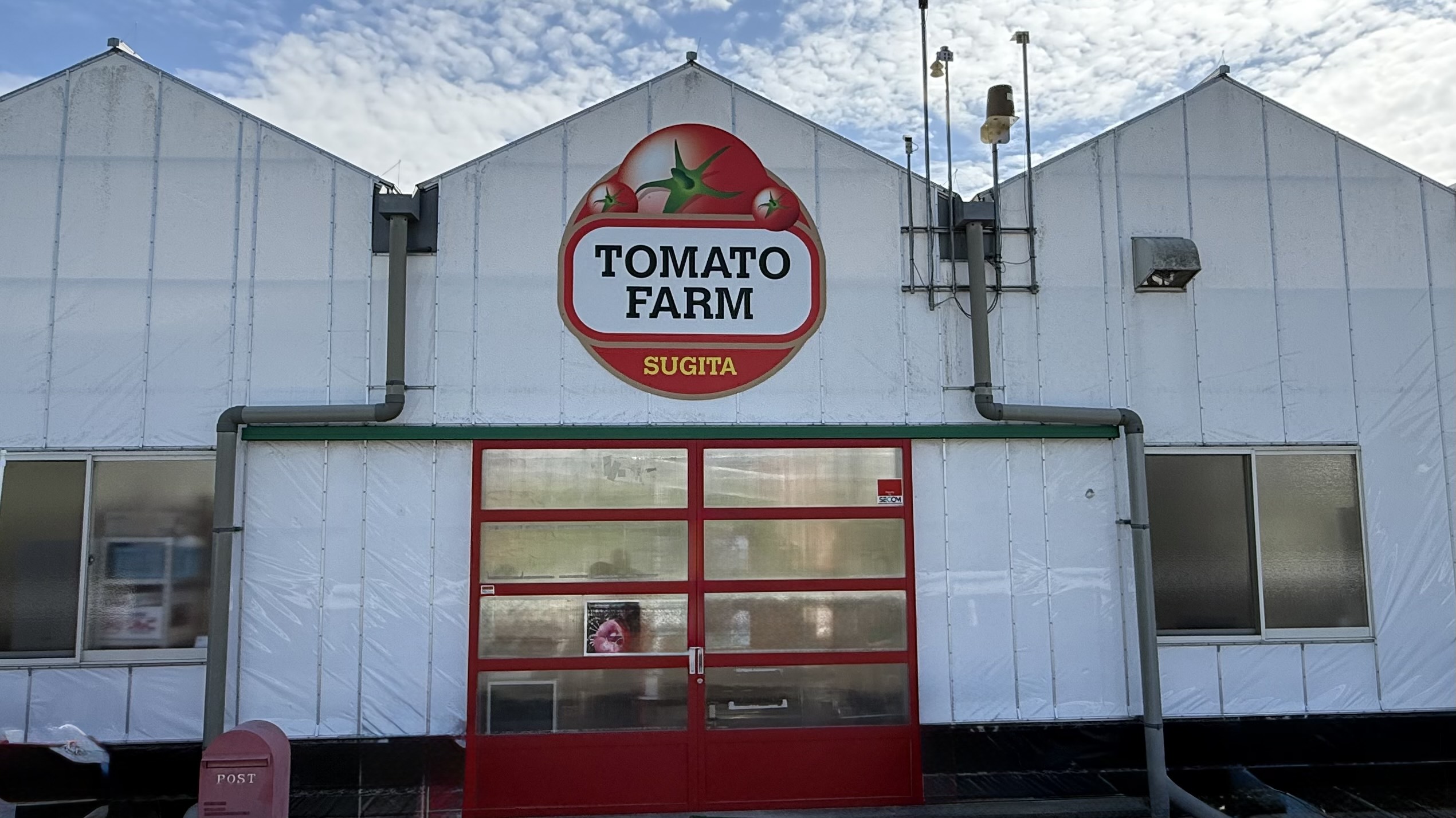 京都杉田農園の温室入口。赤い扉と「TOMATO FARM」の看板が見える外観